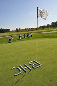 Black Hawk College initials spelled in golf balls on the green