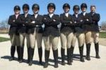 8 people wearing black riding helmets, black jackets, tan pants & black boots