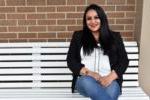 student sitting on a white bench against a brick wall