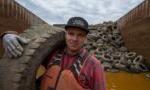 man holding a tire with a pile of tires in the background