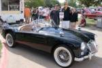 Three people standing next to 1960 MG car with