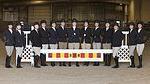 13 hunt seat riders standing in arena with banner