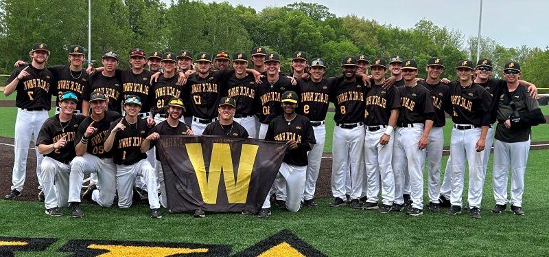 29 BHC baseball players on field smiling at camera with W banner