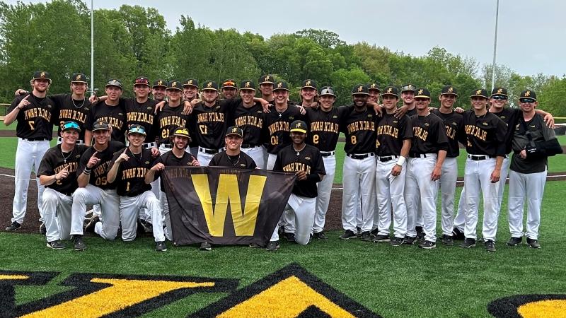 29 BHC baseball players on field smiling at camera with W banner