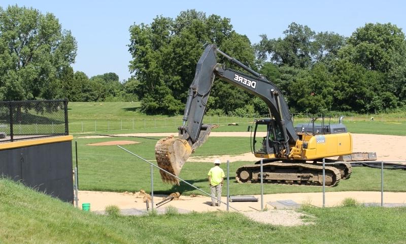 excavator removing fence post at baseball field