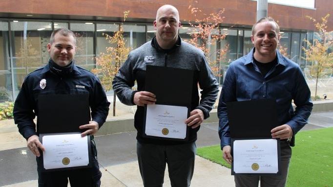 3 people holding certificates of appreciation