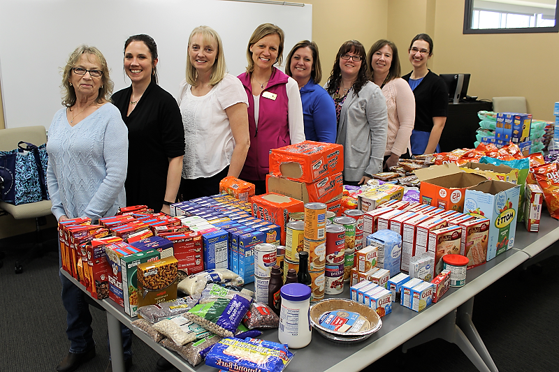 women standing behind a table filled with food pantry items