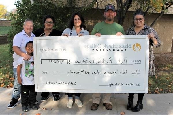 6 people standing outdoors with oversized check