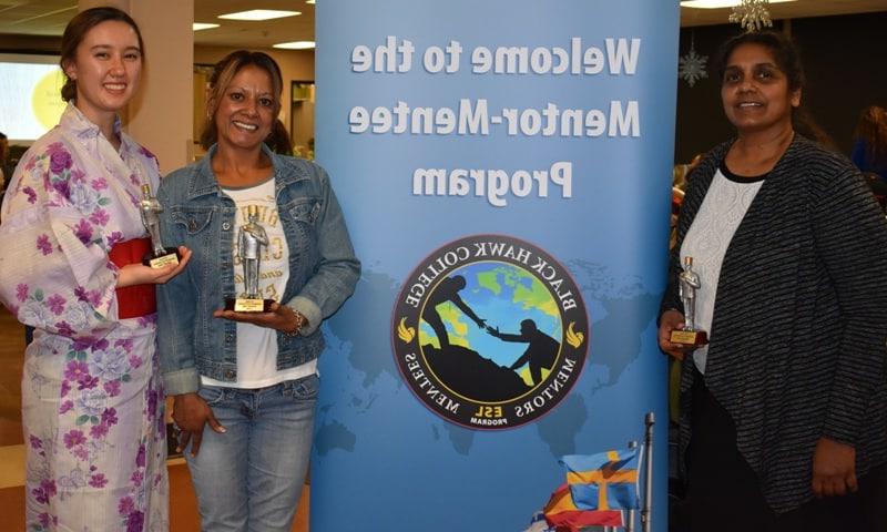 3 women standing by banner holding awards