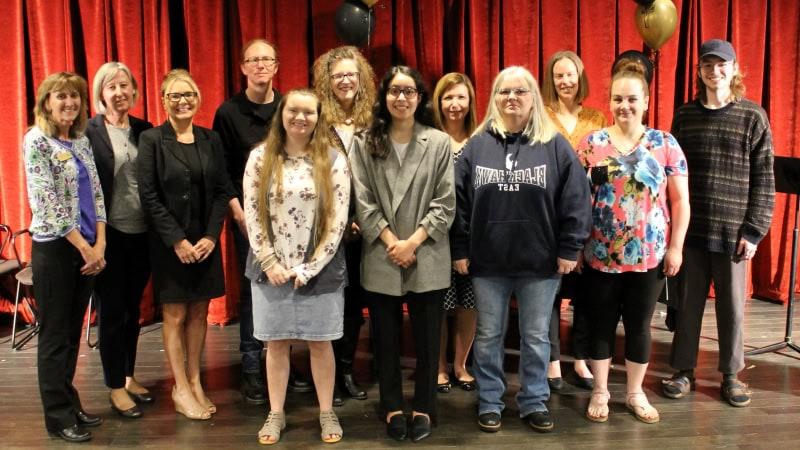 12 people standing & smiling at camera