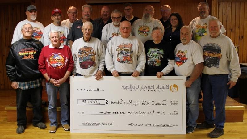 18 people standing with an oversized check